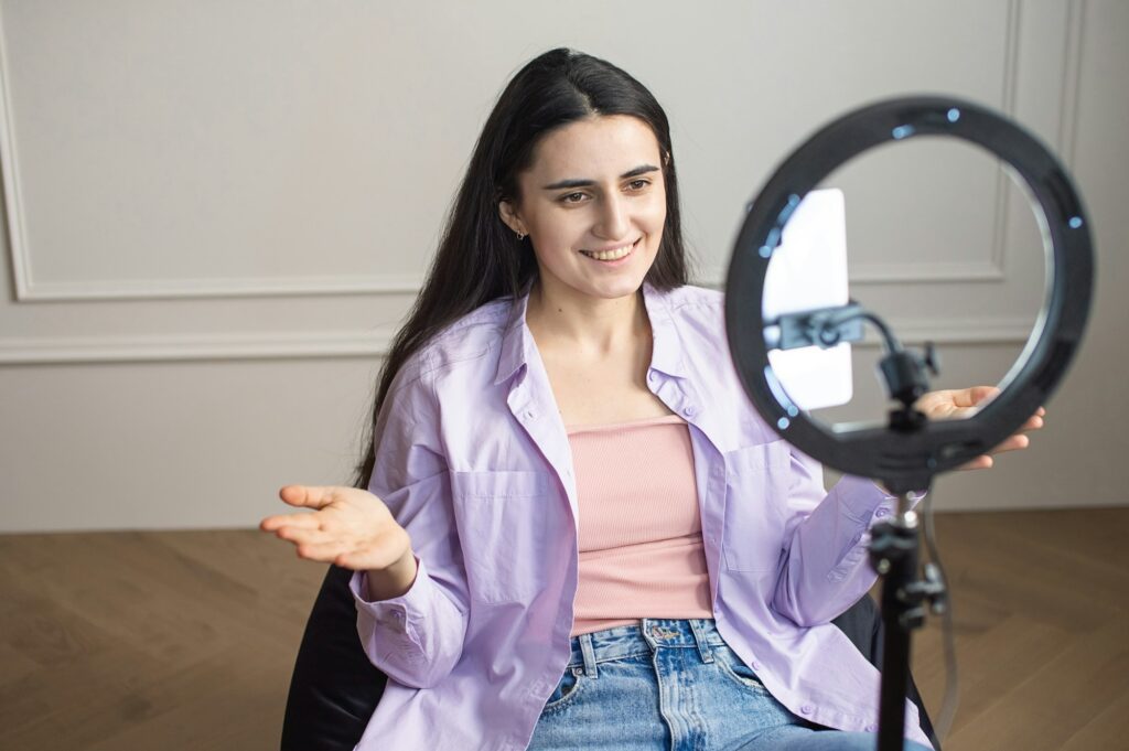 Young woman recording video with LED ring light.